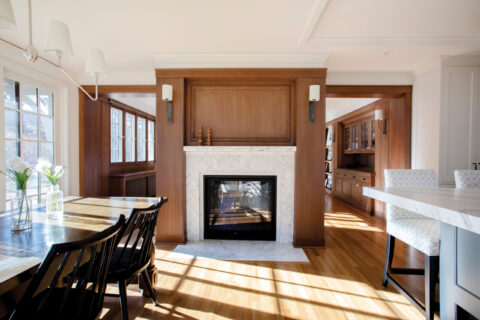 Design build living space highlighting custom millwork, integrated fireplace detailing, and seamless flow between dining and kitchen areas