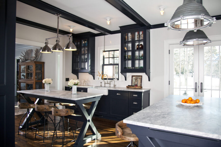 Twin Cities kitchen remodel: dark navy cabinets, marble countertops, wood floors. Industrial pendants illuminate.