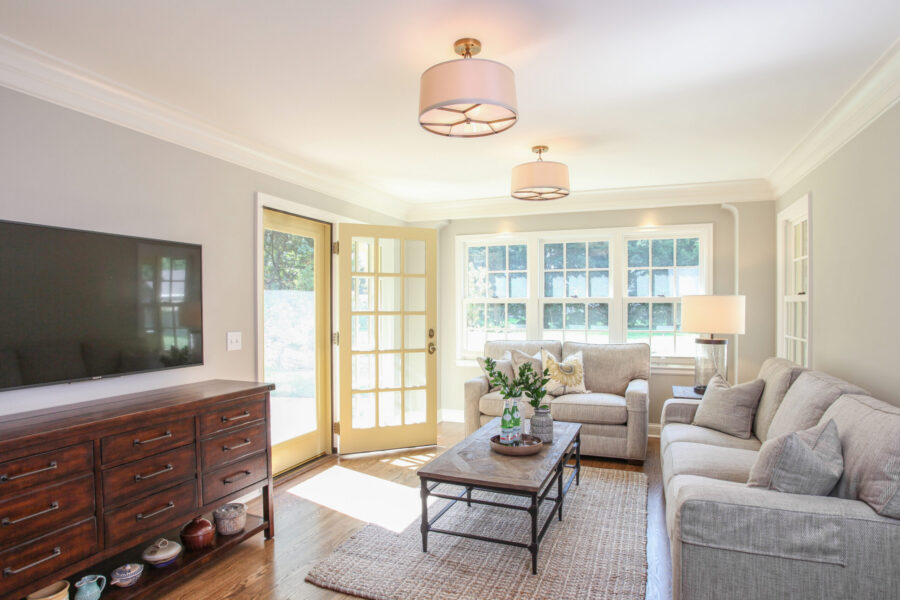 Renovated Twin Cities living room boasts pale walls, rich hardwood, and pendant lights.