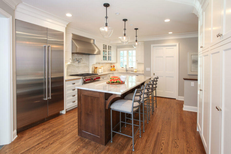 Large, bright kitchen remodel features island seating, stainless appliances, white cabinetry.
