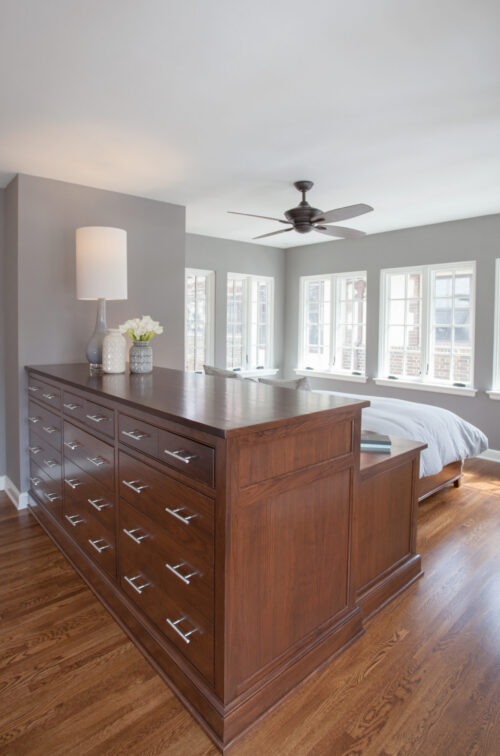 This Twin Cities bedroom home renovation features dark wood custom cabinetry. Windows brighten hardwood floors and grey walls.