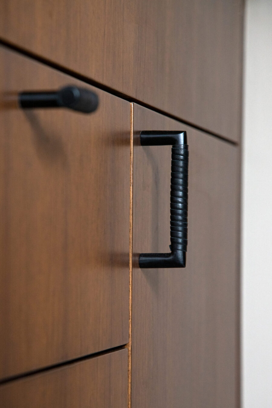 Dark wood cabinetry features modern black textured pull handles, Twin Cities.
