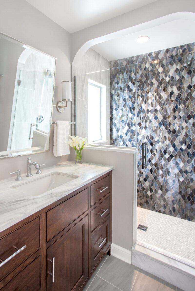 Elegant Twin Cities bathroom remodel features dark-wood vanity, marble, mosaic shower.