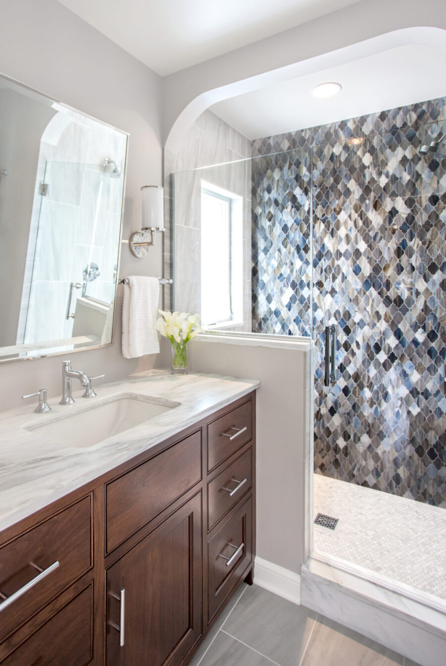 Elegant Twin Cities bathroom remodel features dark-wood vanity, marble, mosaic shower.
