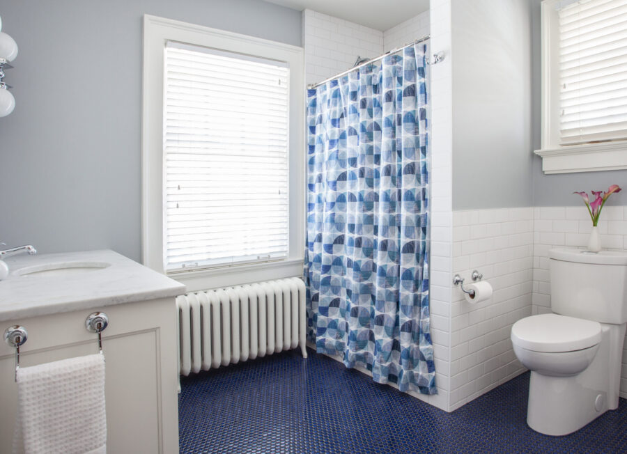 Blue penny tile bathroom features white subway walls, marble vanity, shower.