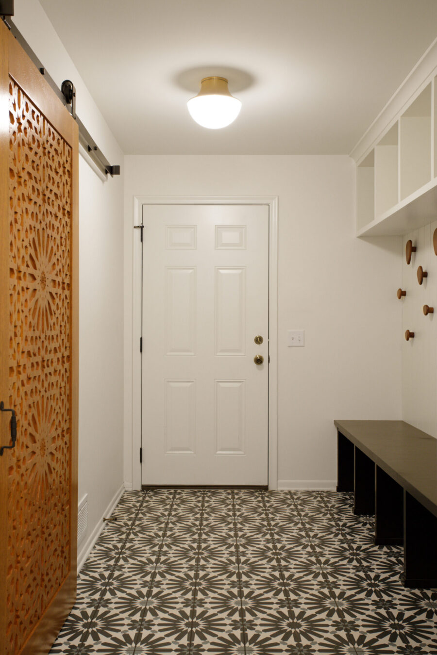 Twin Cities entryway remodel features patterned tile, carved wood door, custom built-ins.