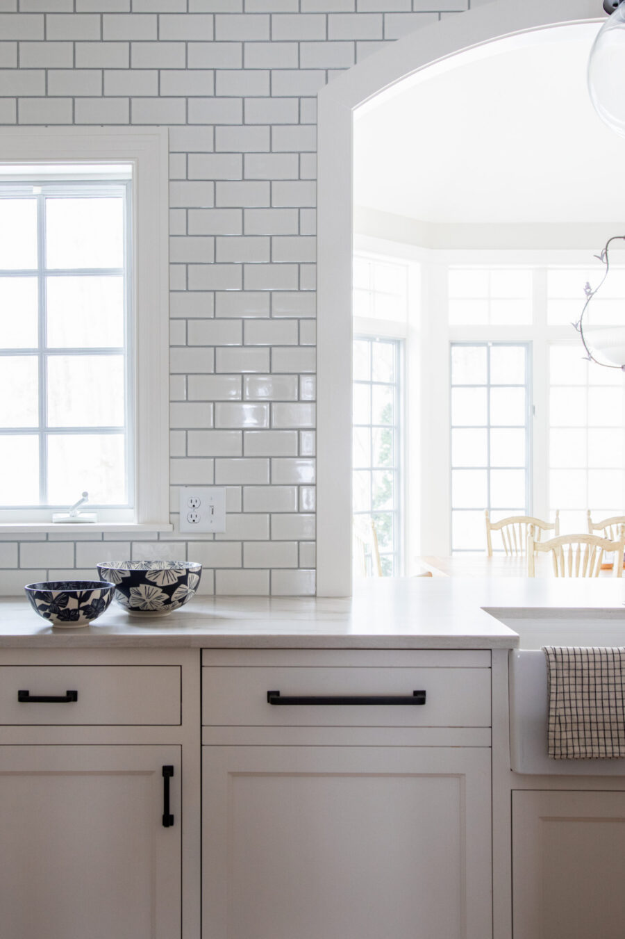 Bright Twin Cities kitchen remodel features white subway tile, modern cabinetry, arched opening.