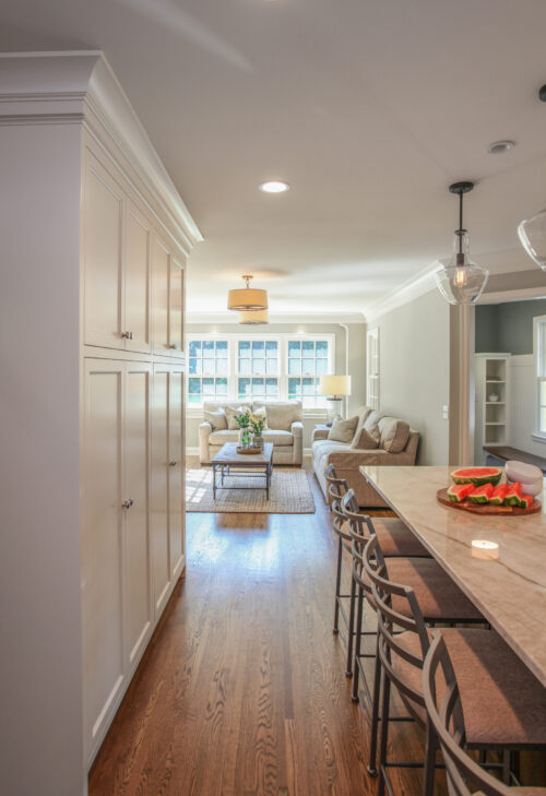 White kitchen cabinetry brightens open-concept living space with dark hardwood.