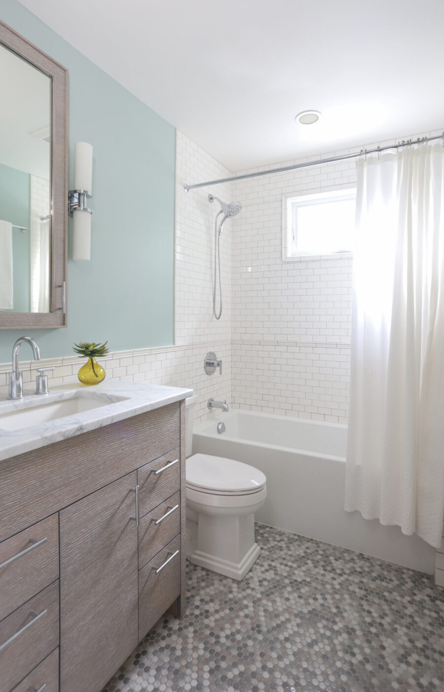 Twin Cities bathroom remodel reveals wood vanity, marble, subway, and penny tiles.