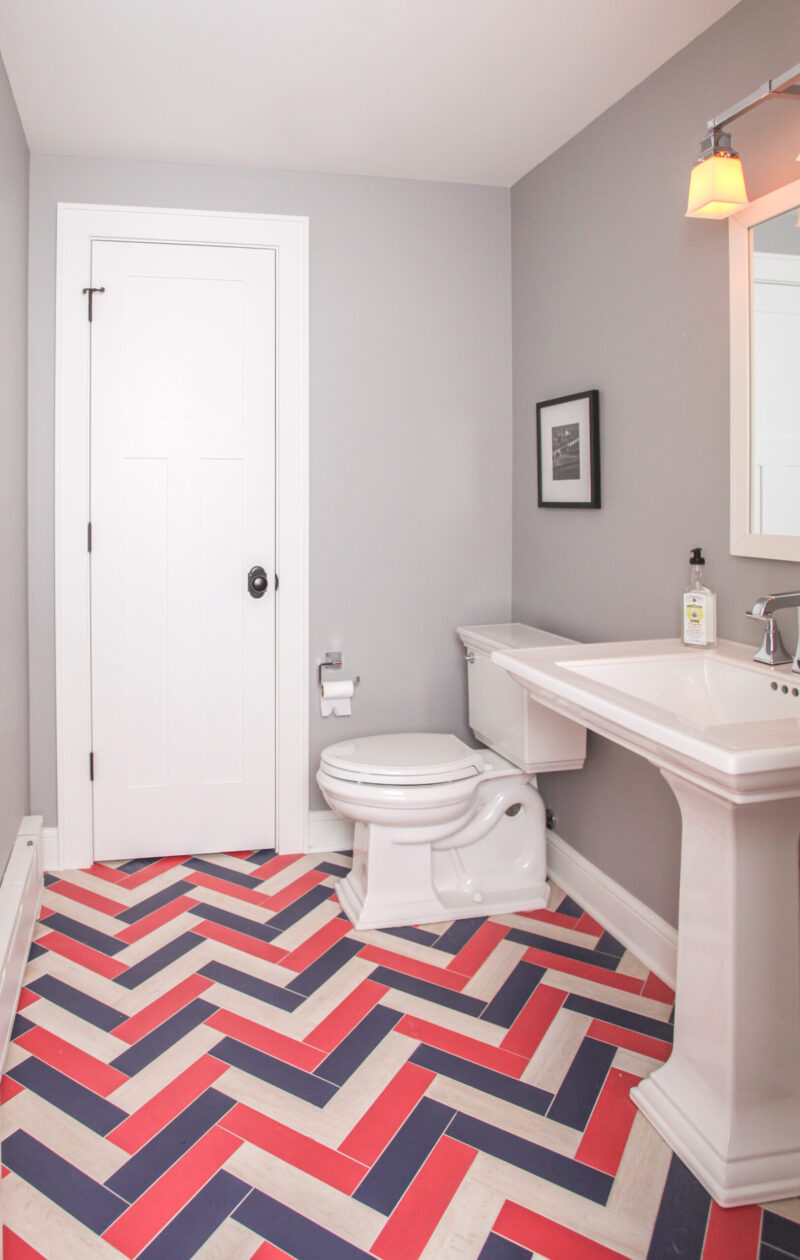 Gray bathroom presents white fixtures, colorful herringbone floor. Twin Cities remodel.