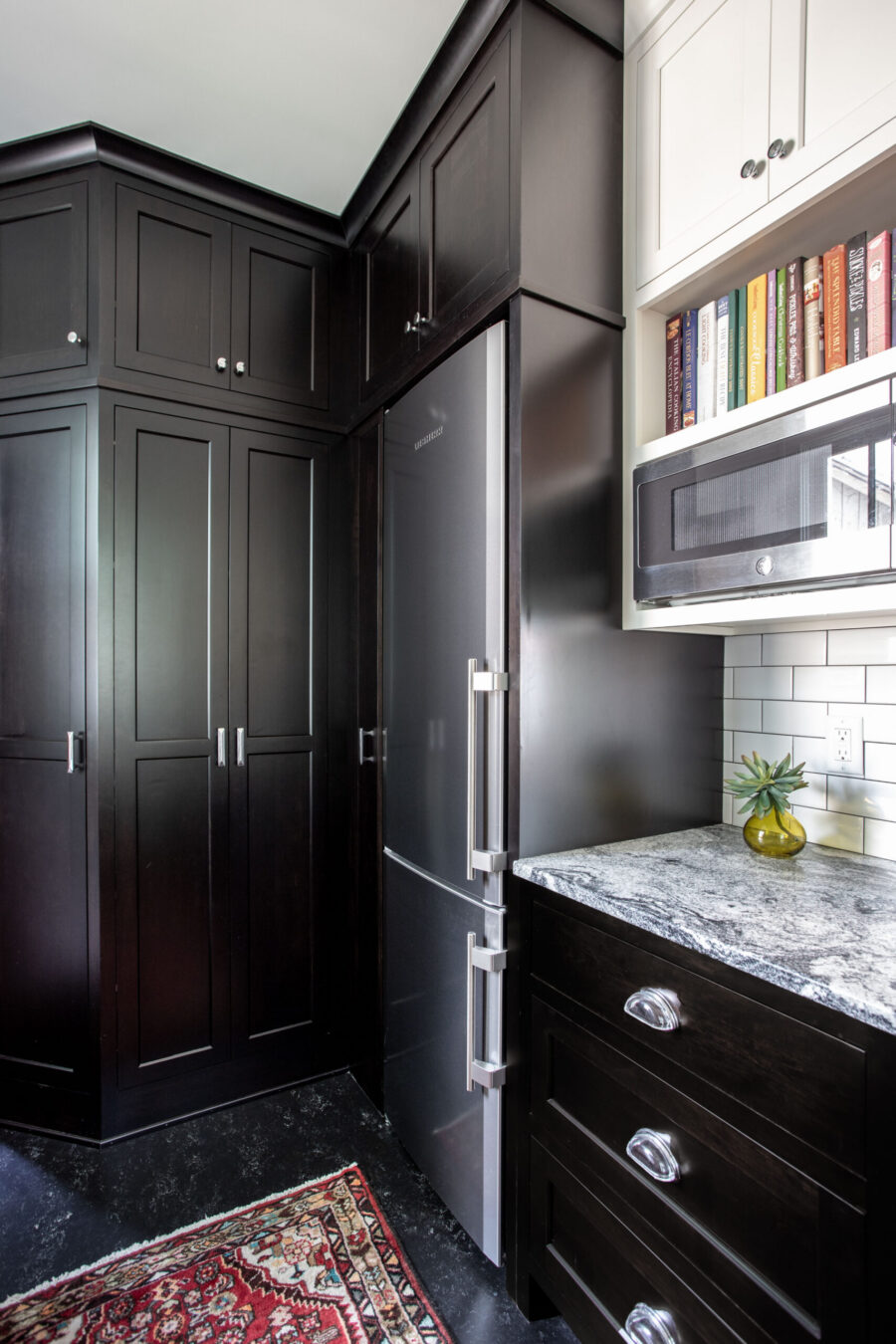 Dark-stained shaker cabinets, gray granite, and stainless appliances enhance this kitchen remodel.