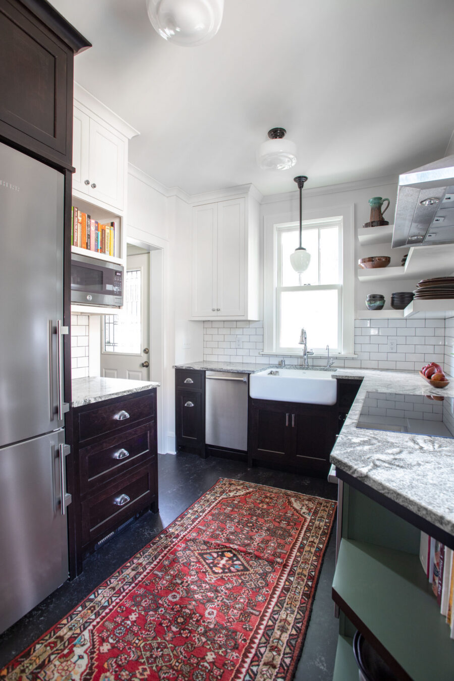 Bright kitchen remodel: white upper, dark base cabinets, granite counters, subway tile backsplash, and stainless appliances.