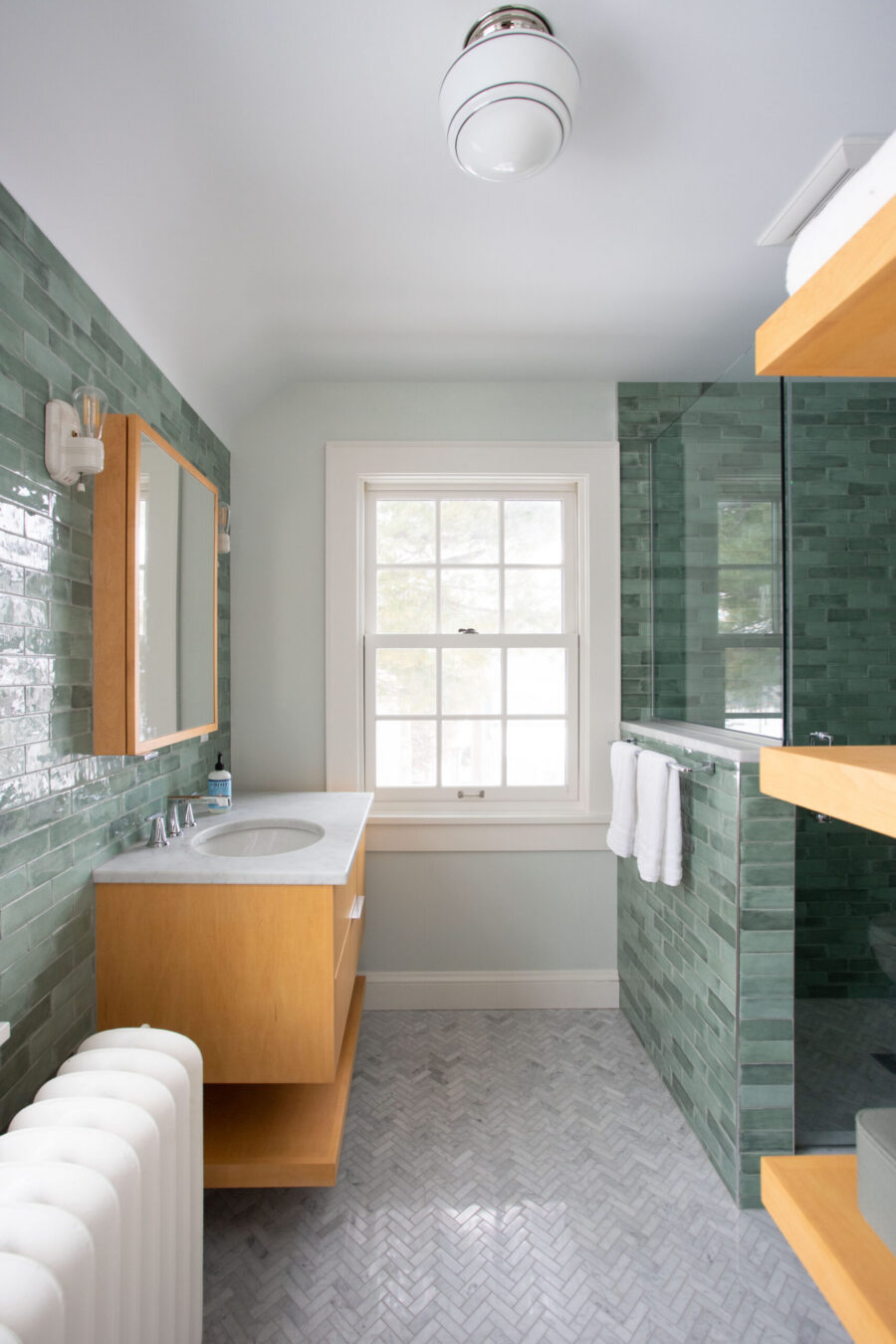 Twin Cities bathroom remodel: glossy green tiled shower, floating wood vanity.