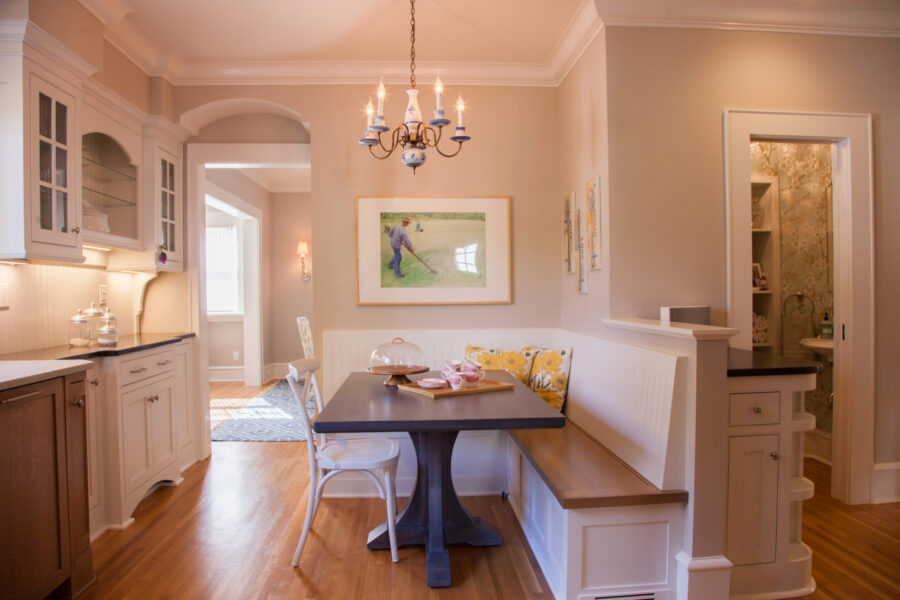 Twin Cities kitchen remodel. Custom white cabinets, dark counters, and a built-in dining banquette complement rich hardwood floors.