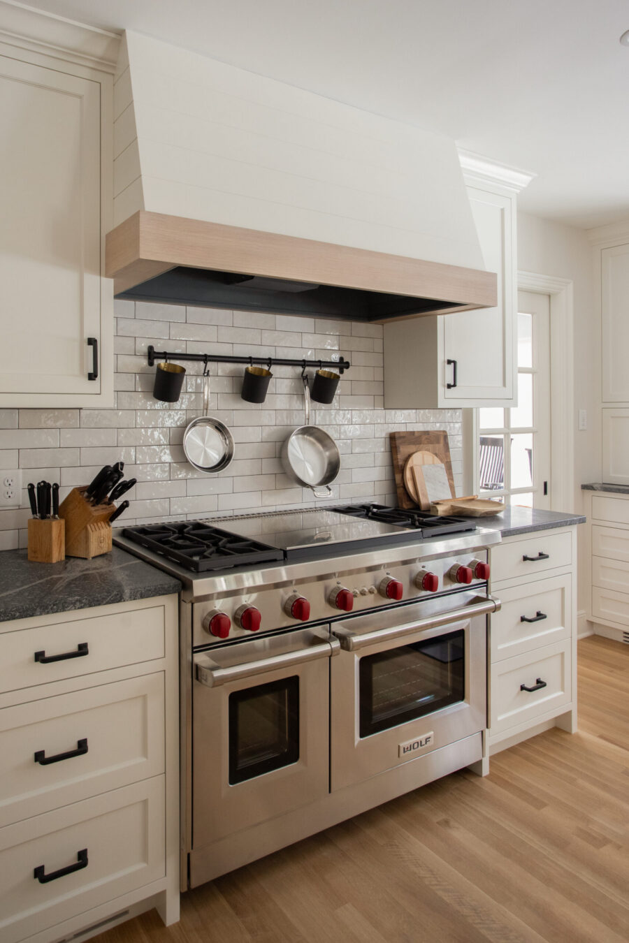 Twin Cities kitchen remodel offers white cabinets, dark counters, subway tile, wood hood, and stainless steel range.