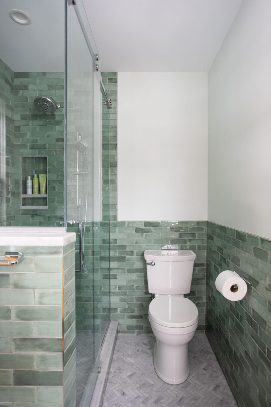 Twin Cities bathroom renovation features green subway tile, glass shower, white toilet.