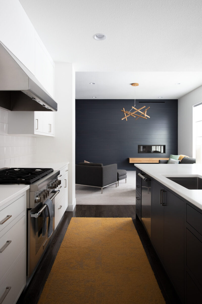 Modern Twin Cities kitchen remodel features dark cabinetry, white counters, and sleek appliances.