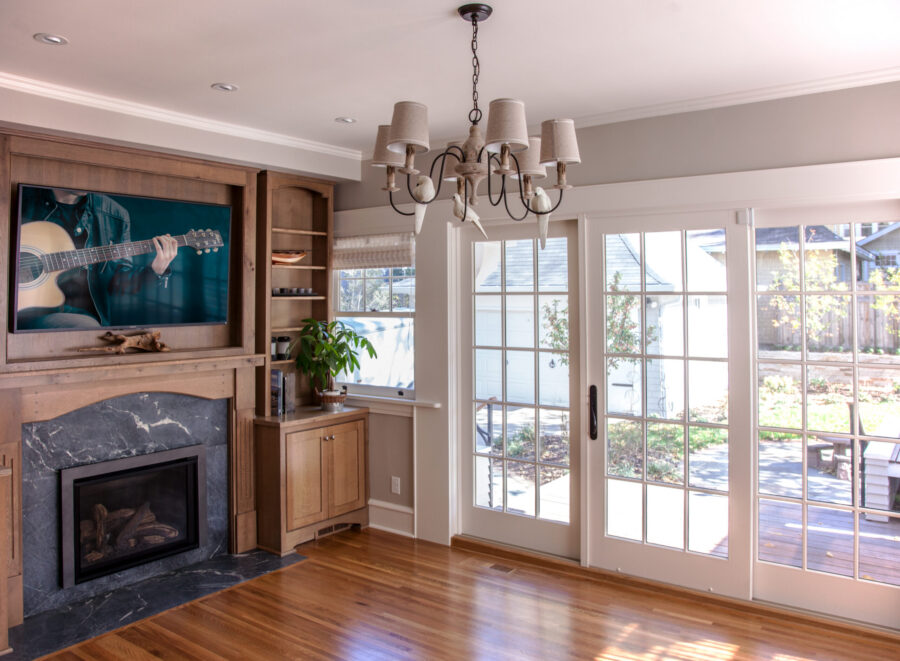 Twin Cities home renovation brightens living room; wood floors, built-ins, marble fireplace, and patio doors.