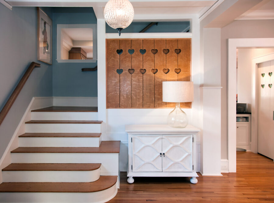 Warm wood stairs, a white cabinet, and a decorative heart panel define this Twin Cities entryway renovation.