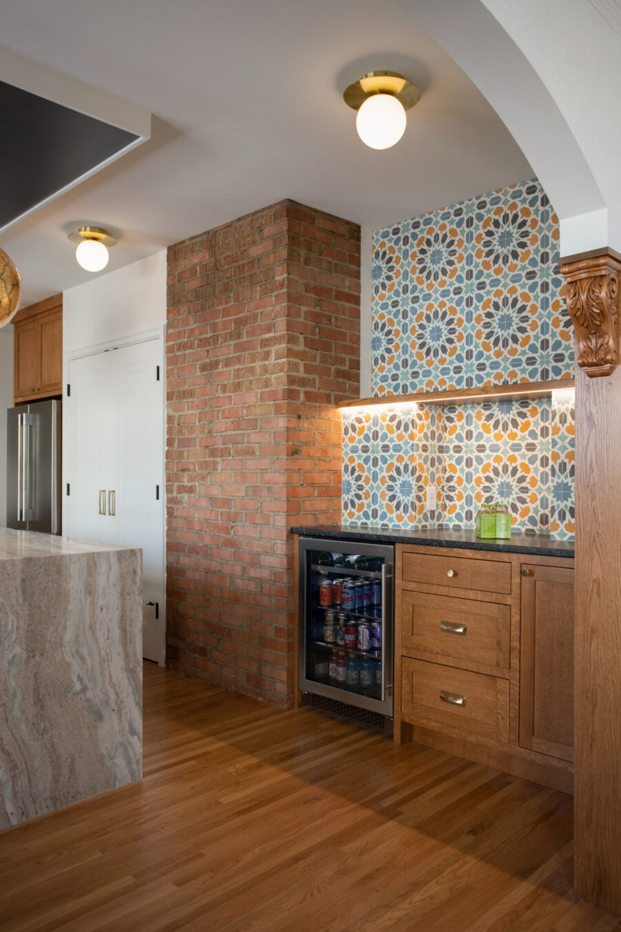Twin-Cities kitchen-remodel features exposed-brick, patterned-tile-backsplash, wood cabinetry, brass lighting.