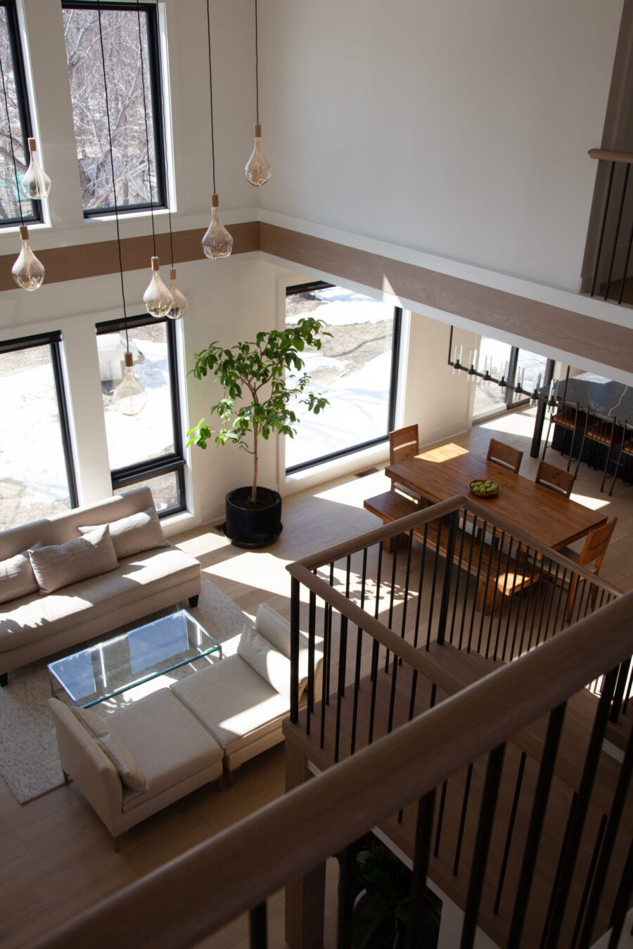 Bright, open-concept Twin Cities home renovation features a two-story living and dining area. Large windows, wood floors, and modern pendant lighting.