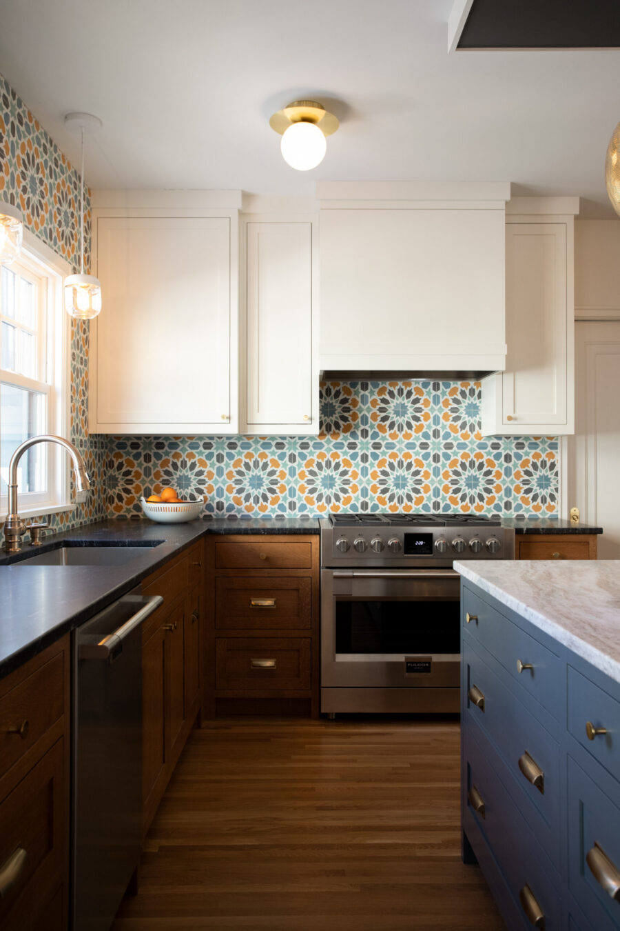 Modern kitchen remodel boasts white cabinets, tile backsplash, dark counters, blue island.