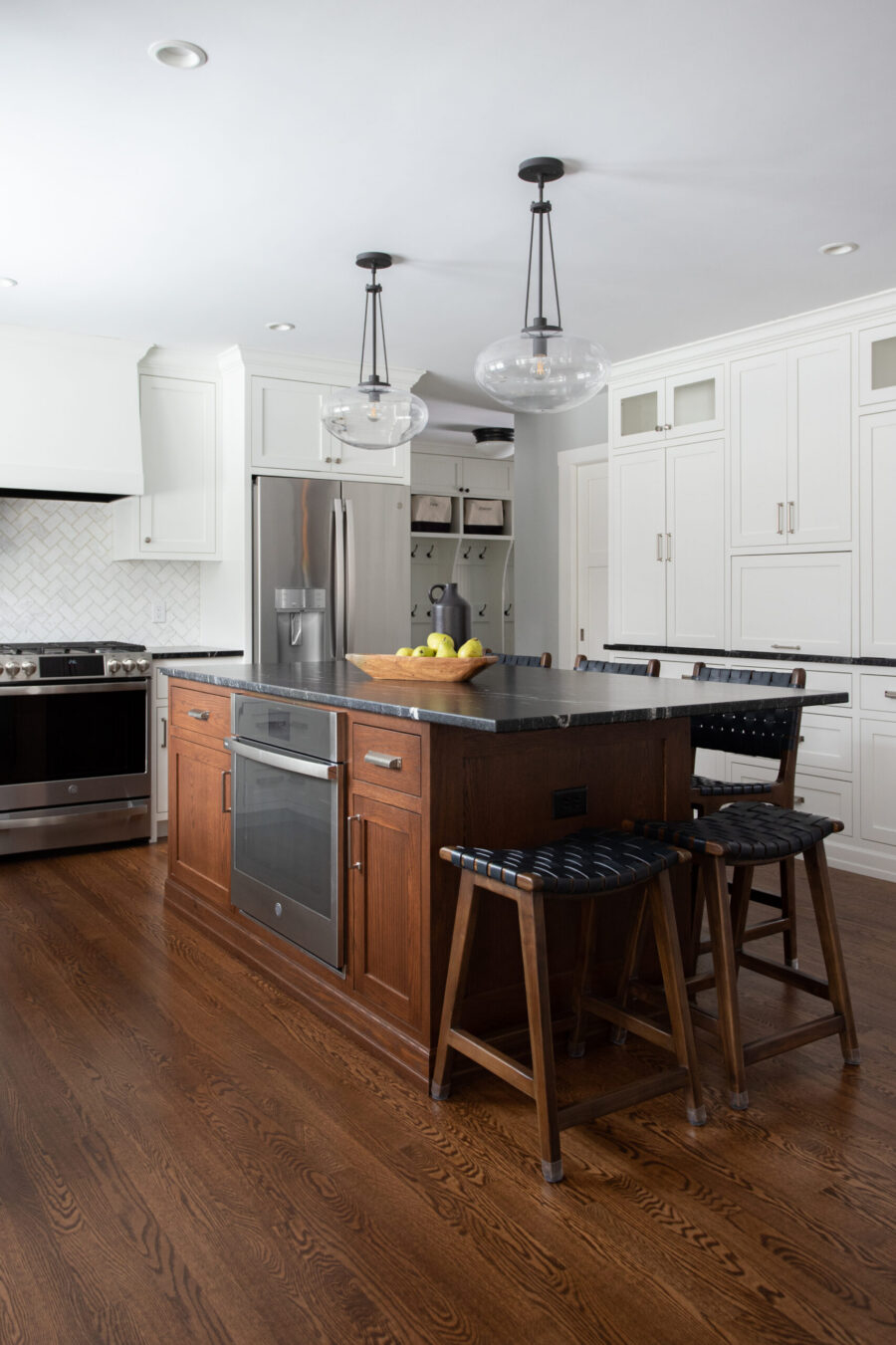 A Twin Cities kitchen remodel features a dark wood island, white cabinets, steel appliances, pendant lights, and hardwood floors.