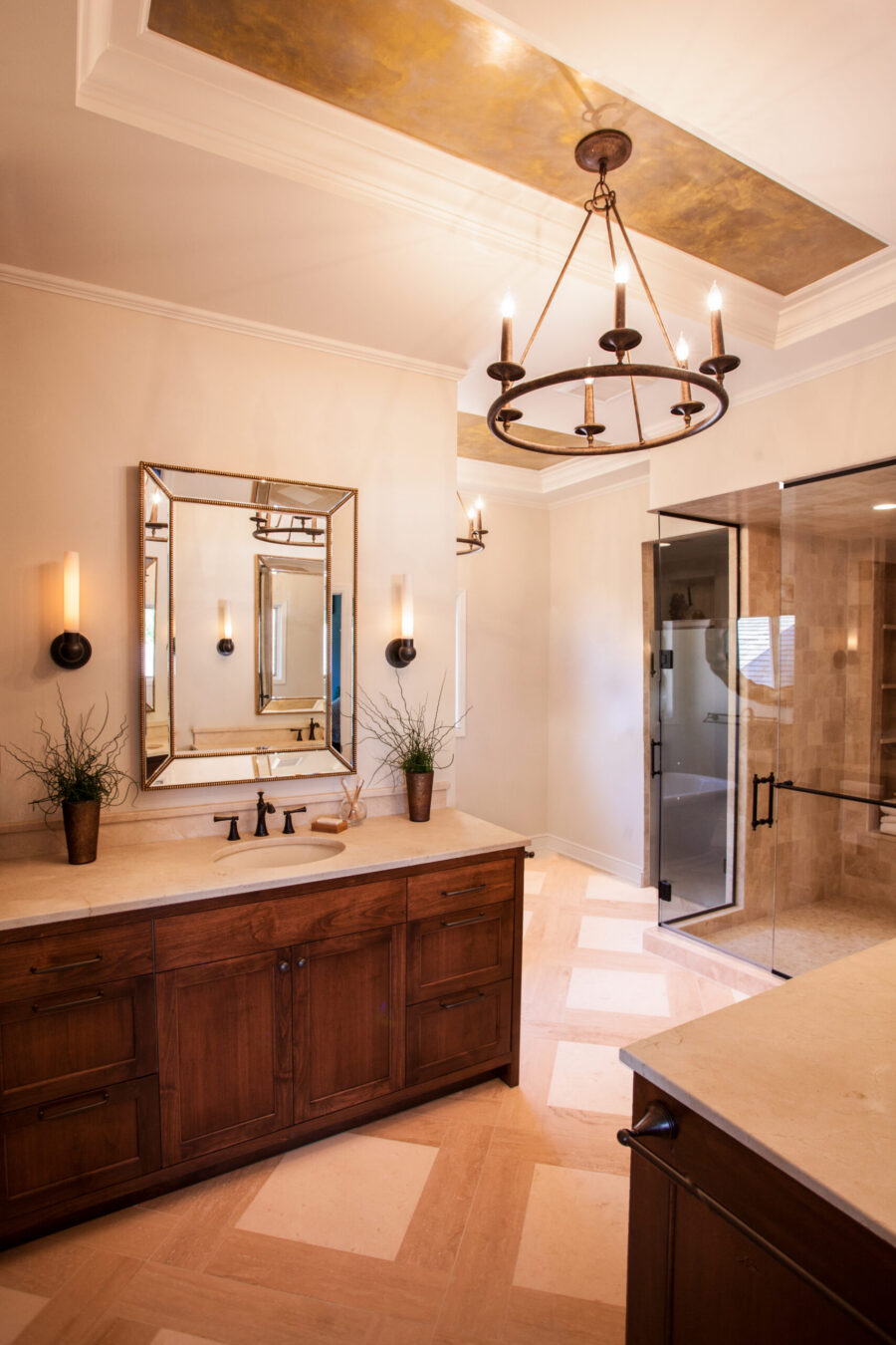 Remodeled bathroom presents dark cabinetry, patterned flooring, glass shower, decorative illumination.