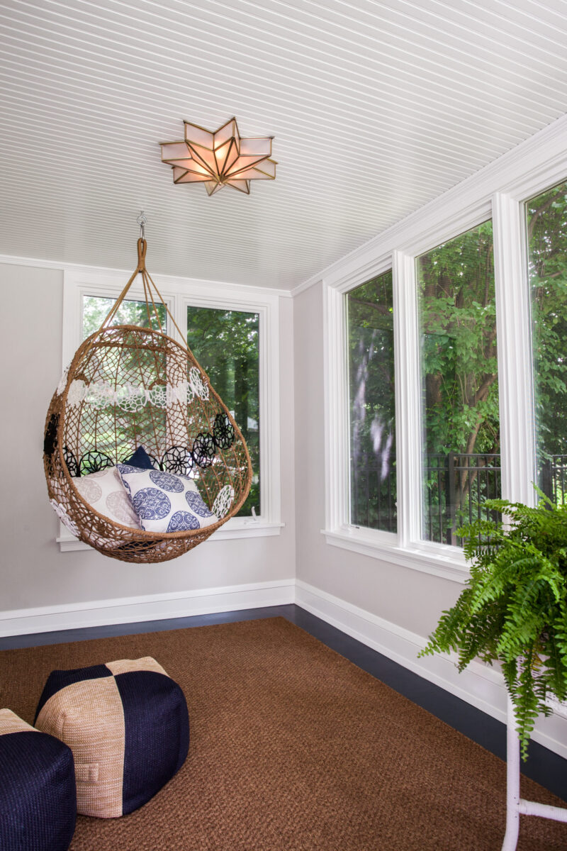 Bright sunroom remodel offers a hanging wicker chair, star ceiling light.