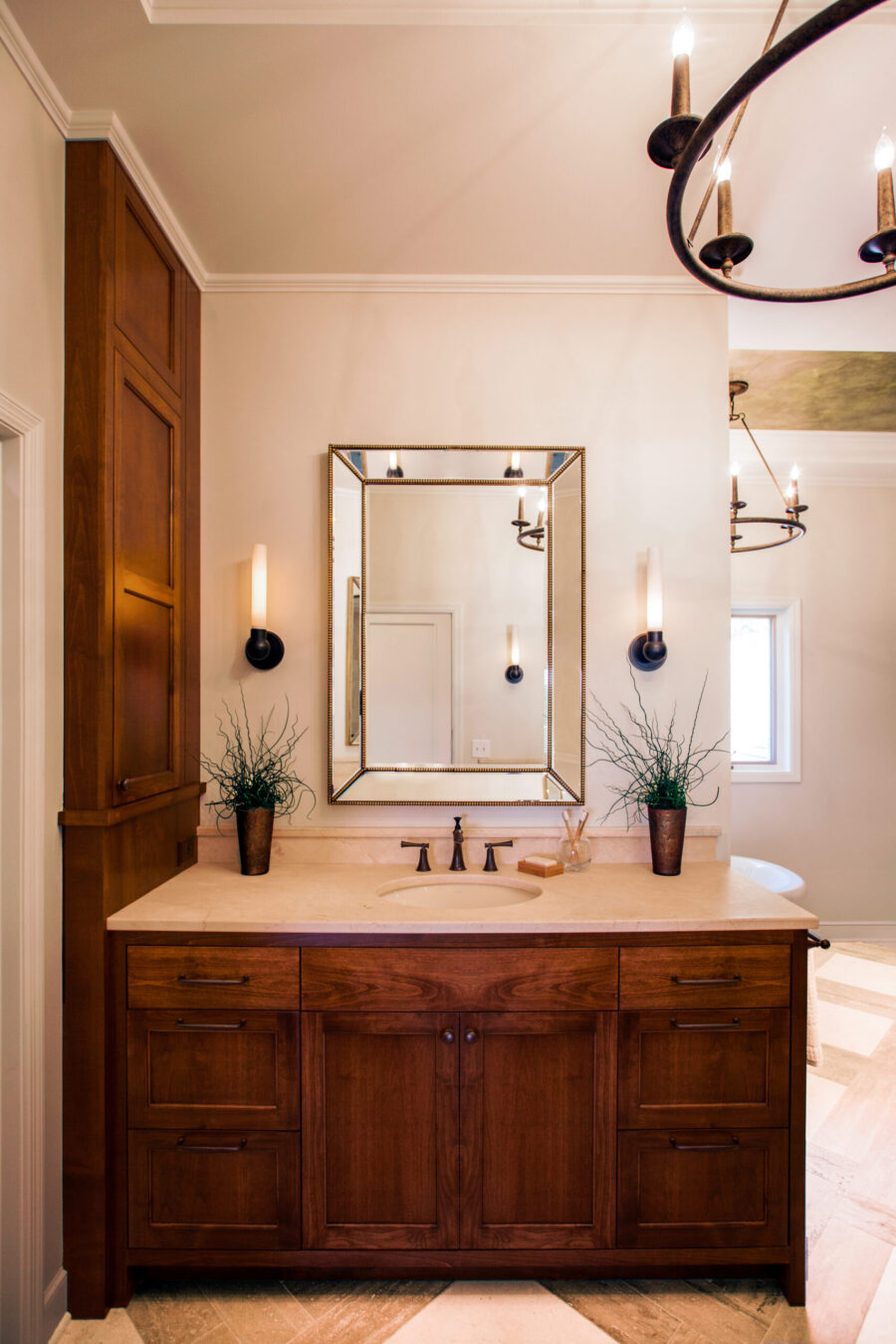 Dark wood vanity, stone counter, mirror, sconces illuminate Twin Cities remodel.