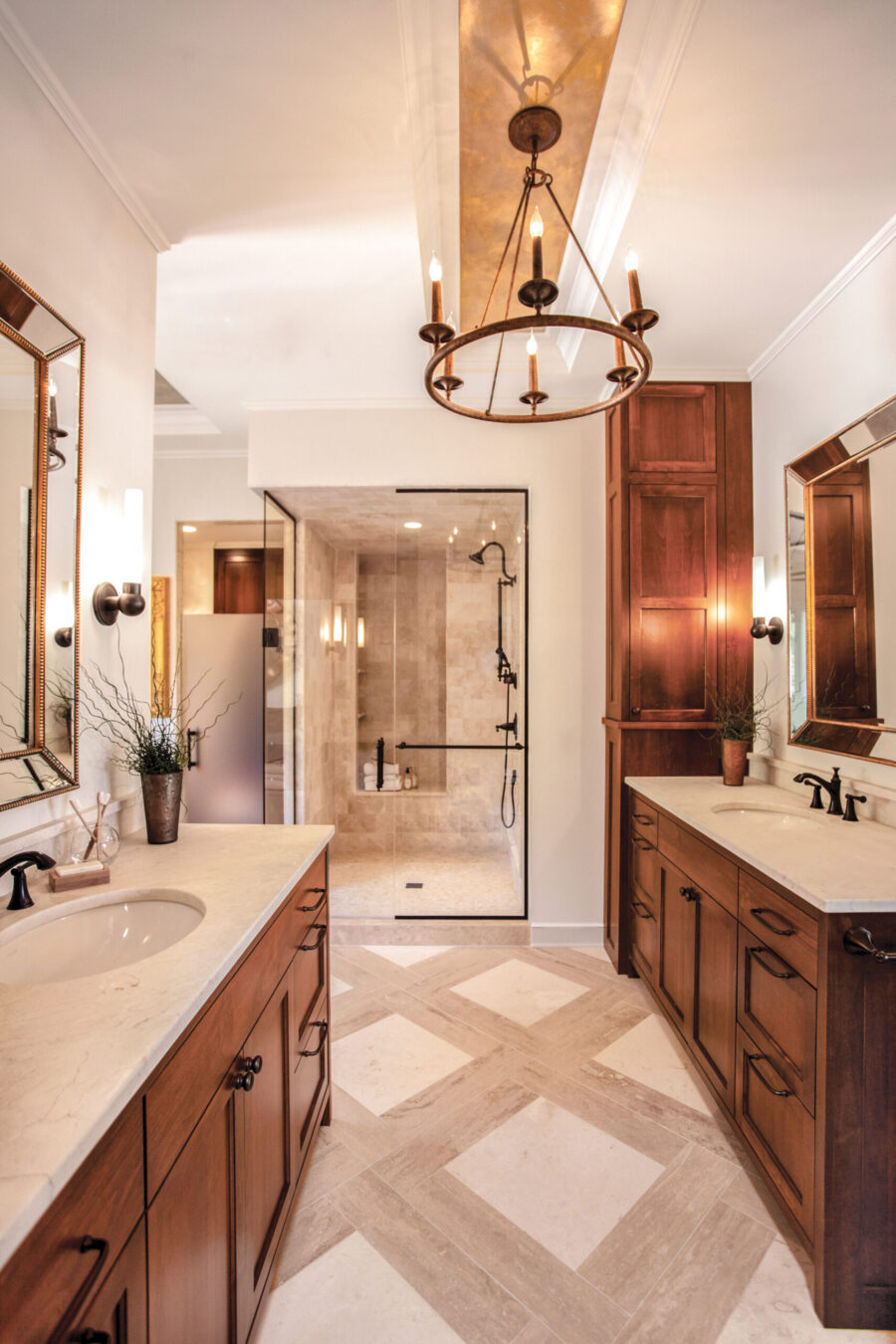 Twin Cities bathroom remodel features dual wood vanities, marble counters, tiled shower, and warm lighting.