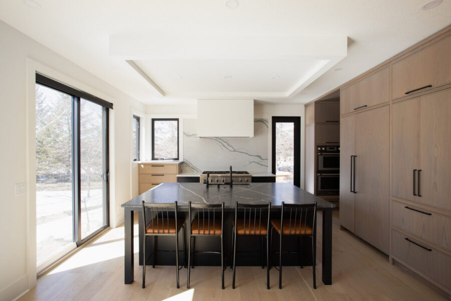 Spacious modern kitchen remodel offers light-toned cabinetry, dark island, impressive natural lighting.