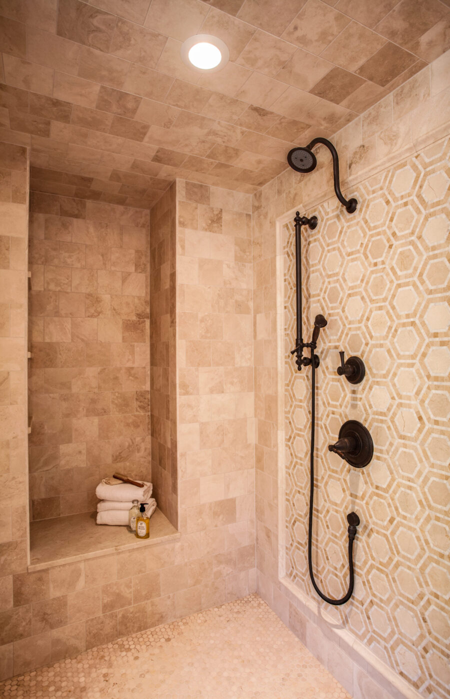Twin Cities bathroom remodel features beige stone tiles, hex mosaic, oil-rubbed bronze fixtures.