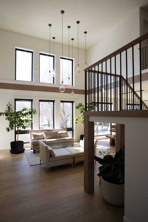 Bright, modern Twin Cities living area features high ceilings, wood floors, elegant stairwell.