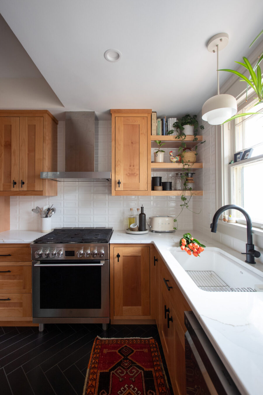 Twin Cities kitchen remodel incorporates natural wood cabinetry, quartz, and dark herringbone flooring.