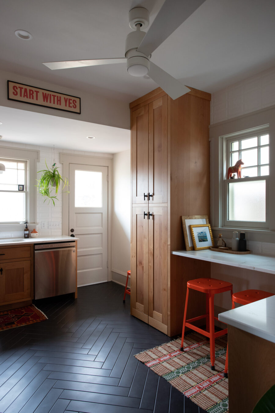 Twin Cities kitchen renovation features light wood cabinetry, dark herringbone floor, and white countertops.