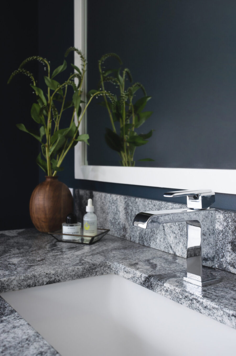 Contemporary Twin Cities bathroom displays dark walls, granite countertop, chrome faucet.
