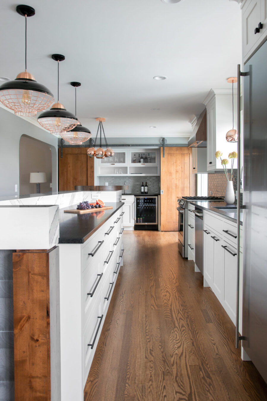 Twin Cities kitchen remodel. White cabinetry, black counters, hardwood, copper pendant lights.