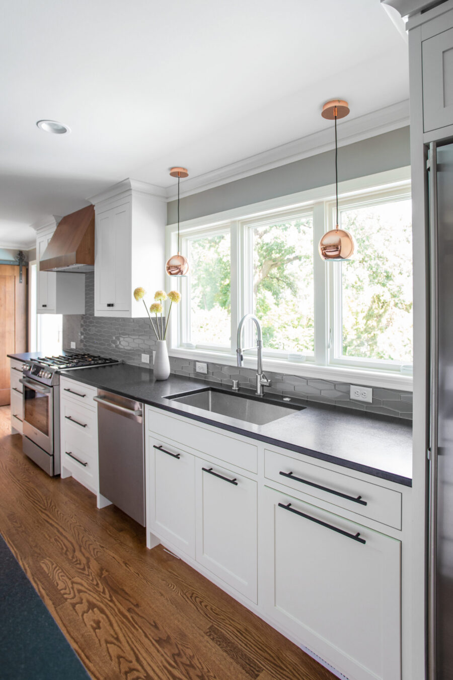 Renovated Twin Cities kitchen features white cabinetry, dark stone, wood flooring.