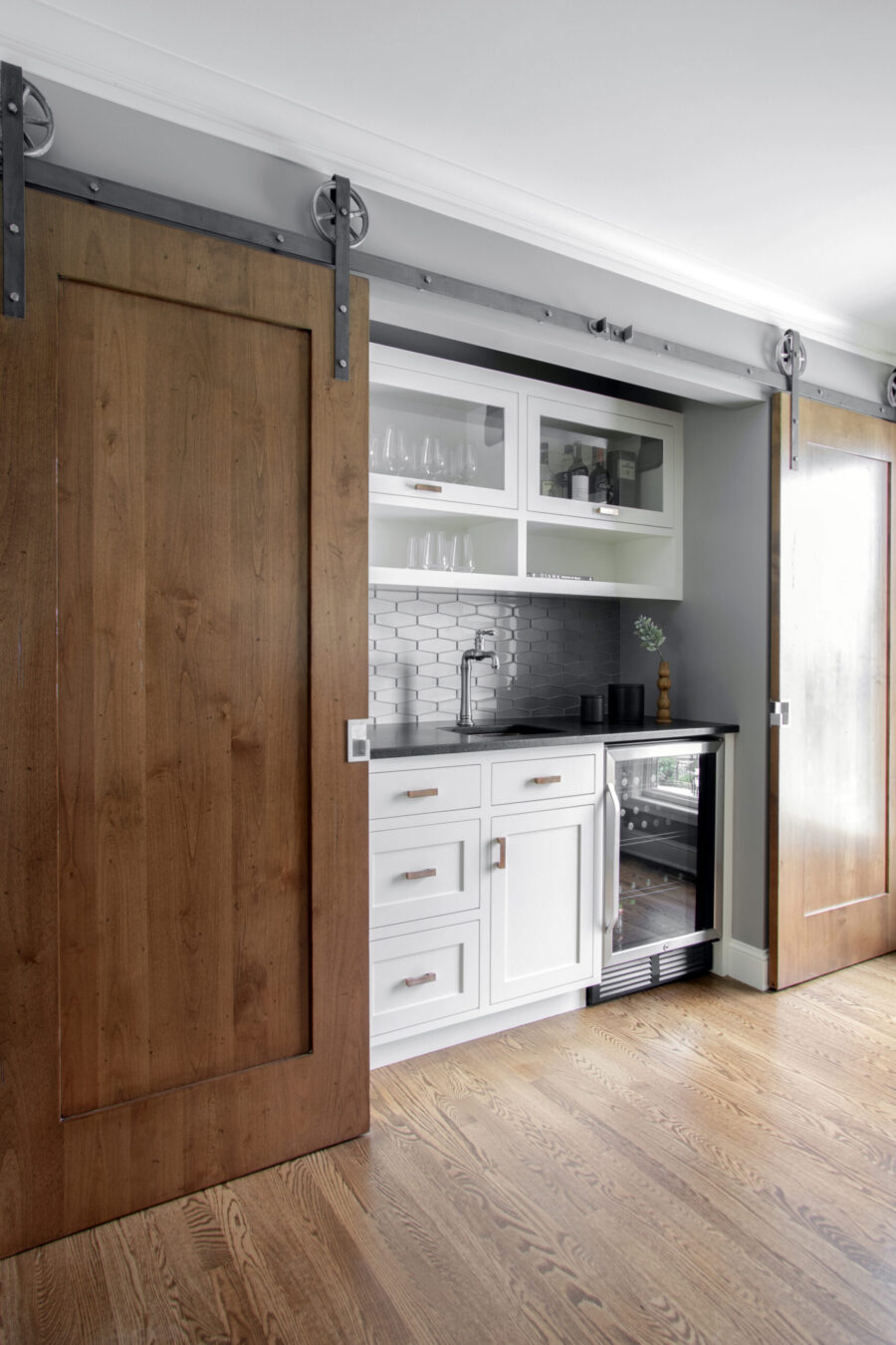 Wet bar remodel: white cabinets, dark counter, hexagon tile, wood barn doors, hardwood floors, Twin Cities.