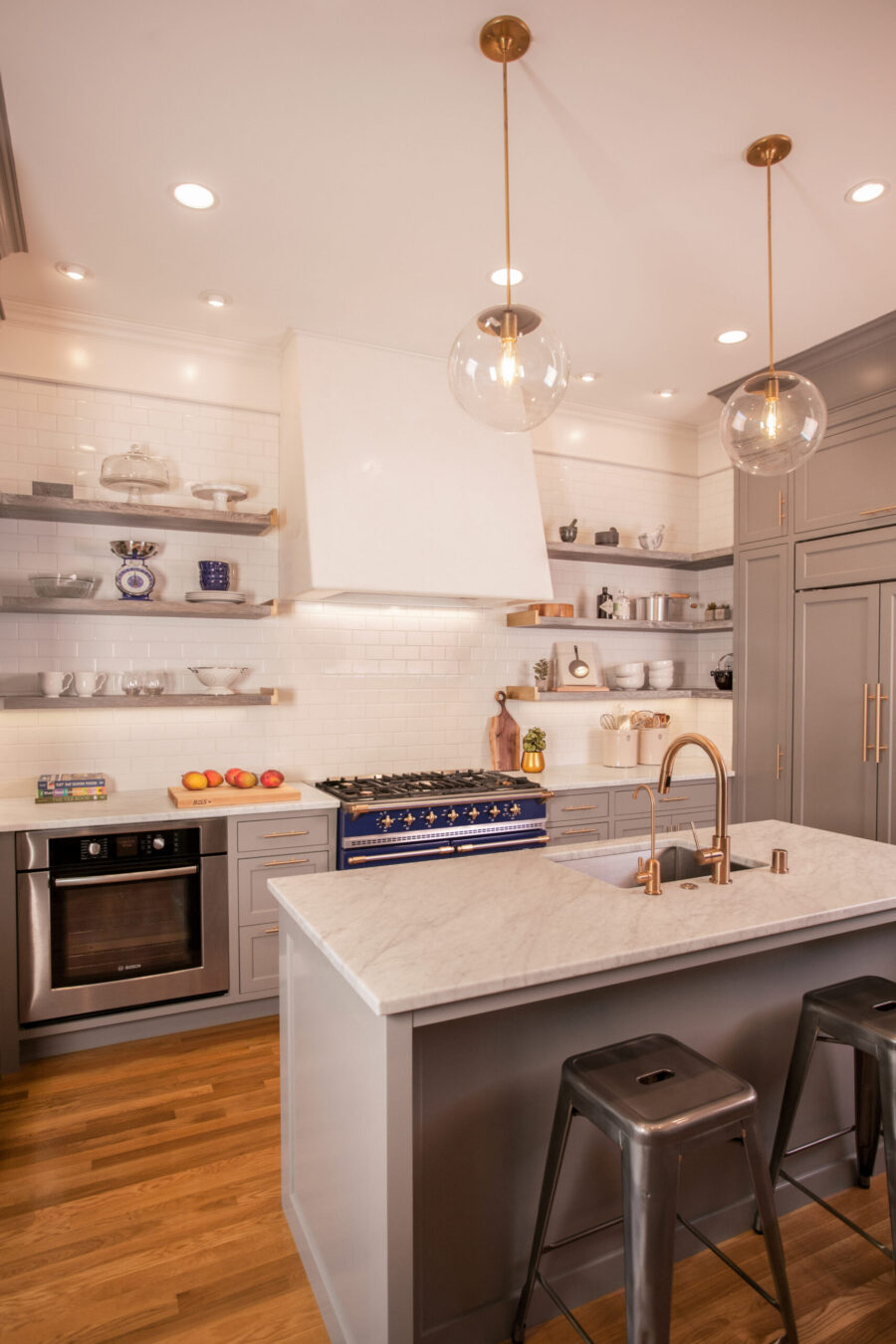 Grey-cabinetry, marble-countertops, and blue-range highlight a modern kitchen remodel.