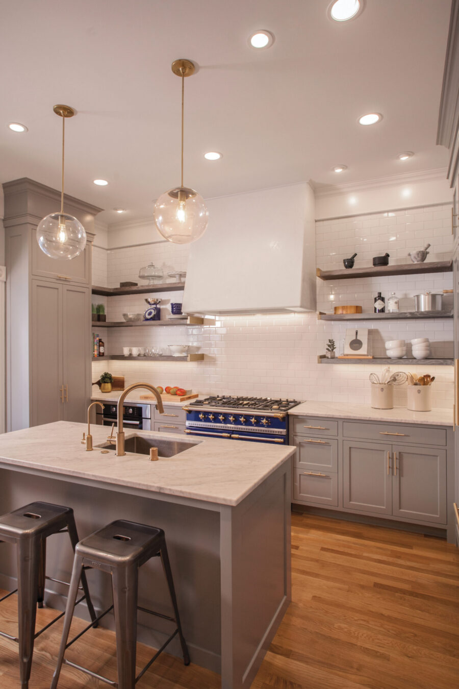 Twin Cities kitchen remodel features grey cabinetry, a marble island, blue range, and bright overhead lighting.