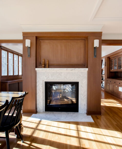 Open-plan living-dining-kitchen design-build features marble fireplace, custom wood paneling. Twin Cities.