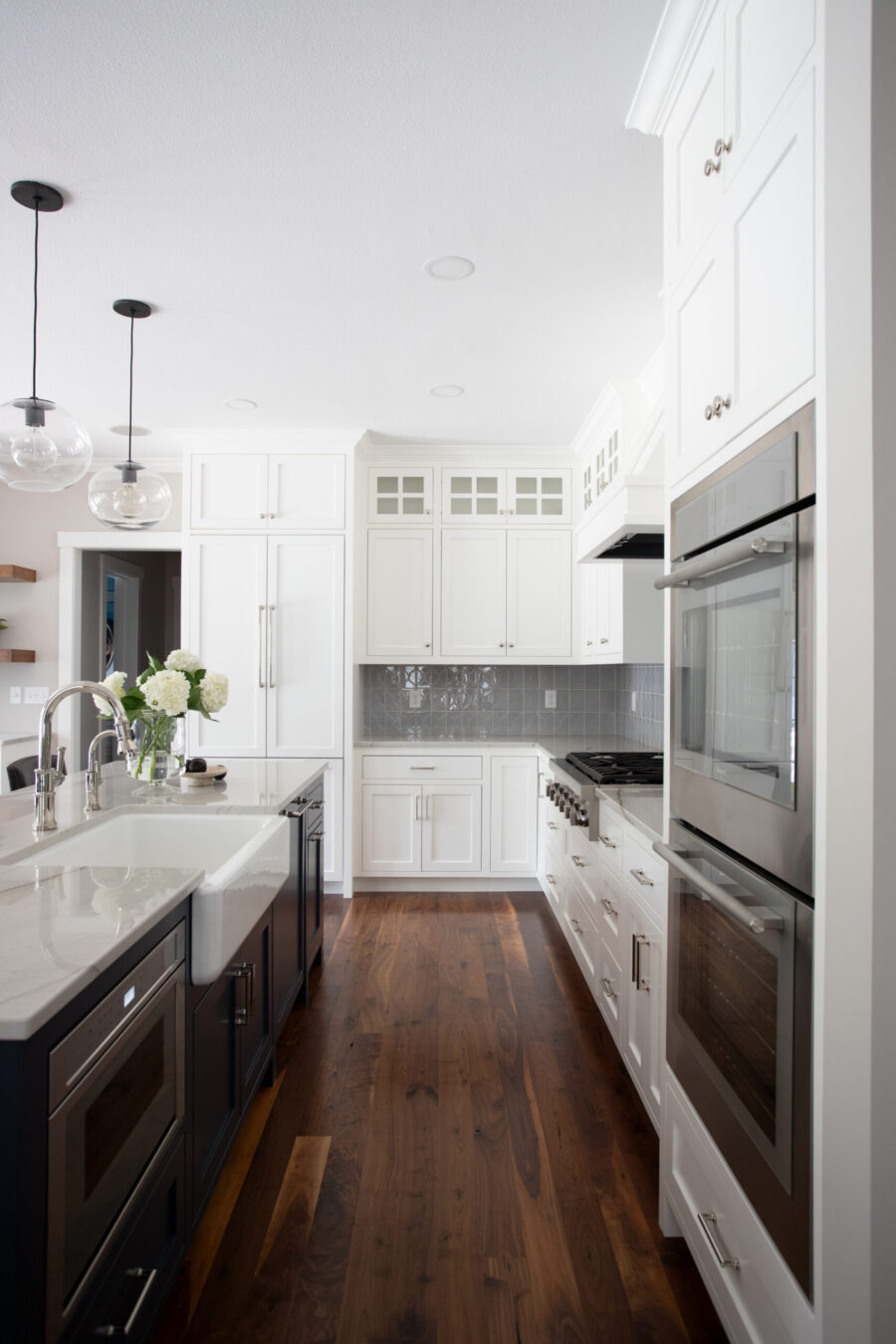 This Twin Cities kitchen remodel features bright white shaker cabinets, dark island, quartz counters, and dark wood floor.