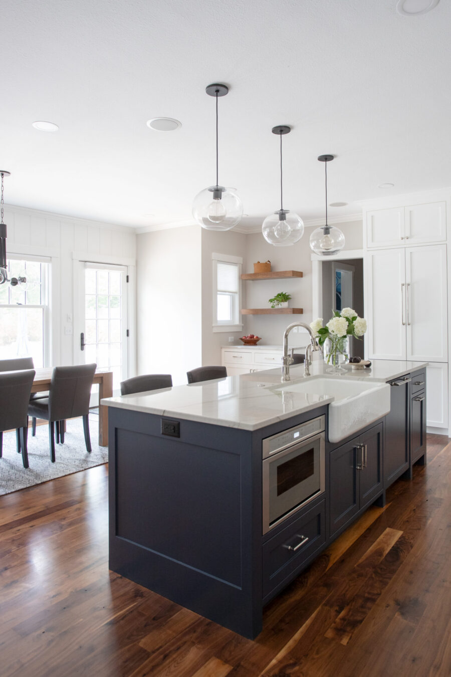 This bright Twin Cities kitchen remodel features a large navy island, white counters, and rich wood floors.