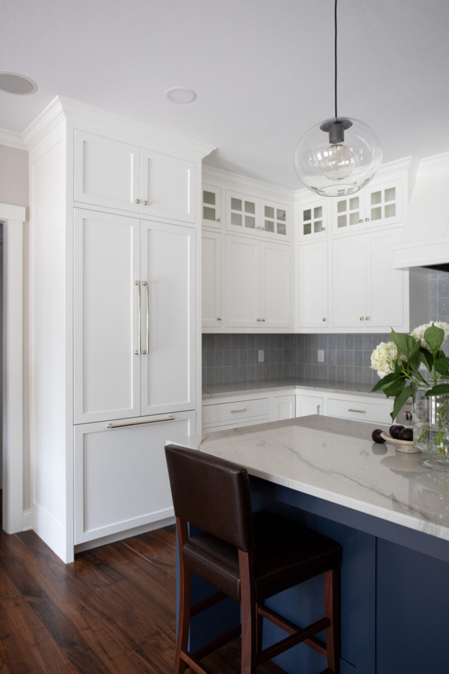 Kitchen remodel: white cabinets, navy island, quartz counters, dark wood floors.