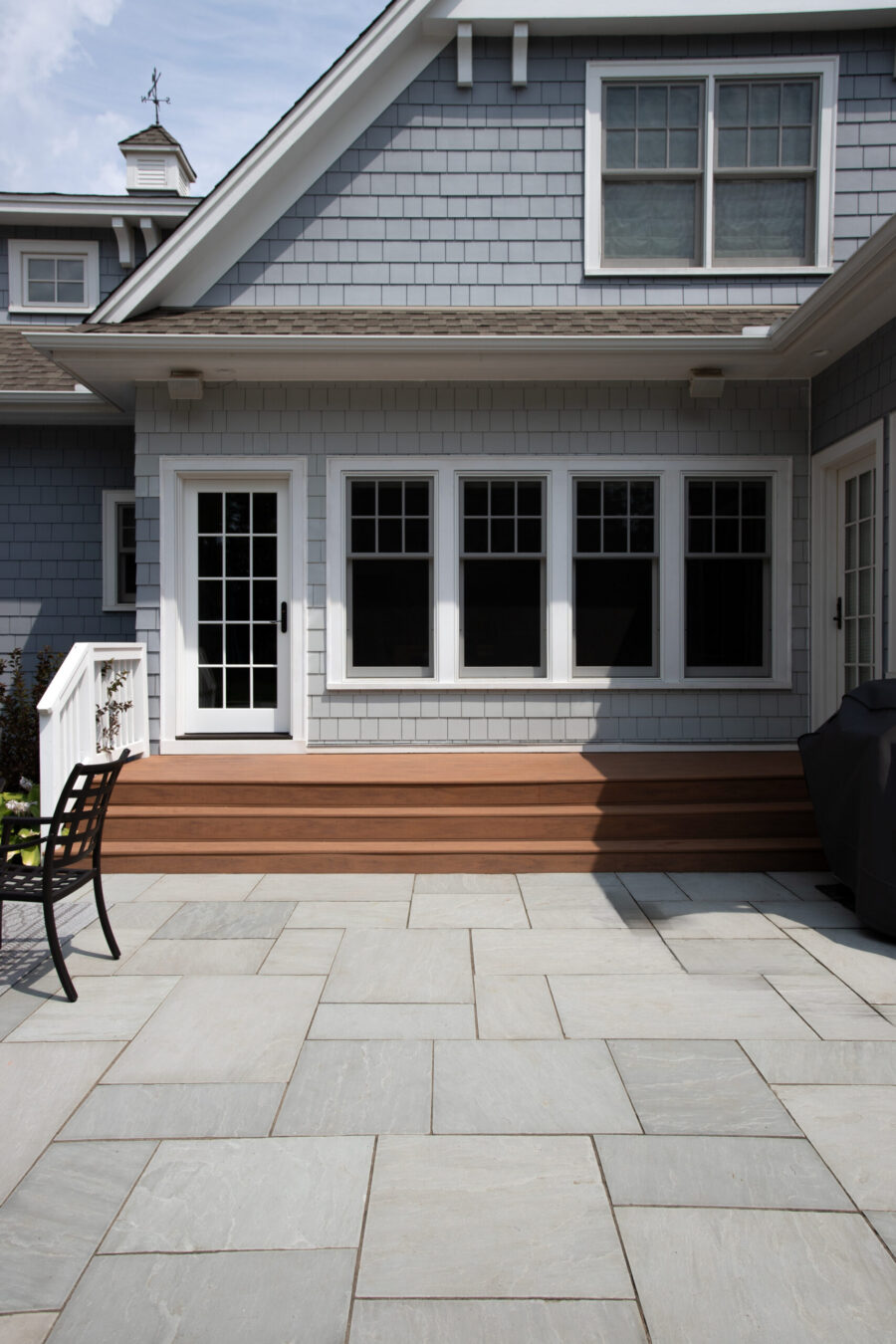 Renovated grey shingle exterior, multi-level wood deck, bluestone patio, design-build.