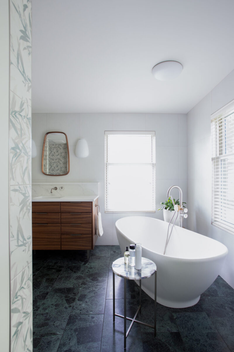 Refined Twin Cities bathroom remodel displays freestanding bathtub, dark green marble flooring.