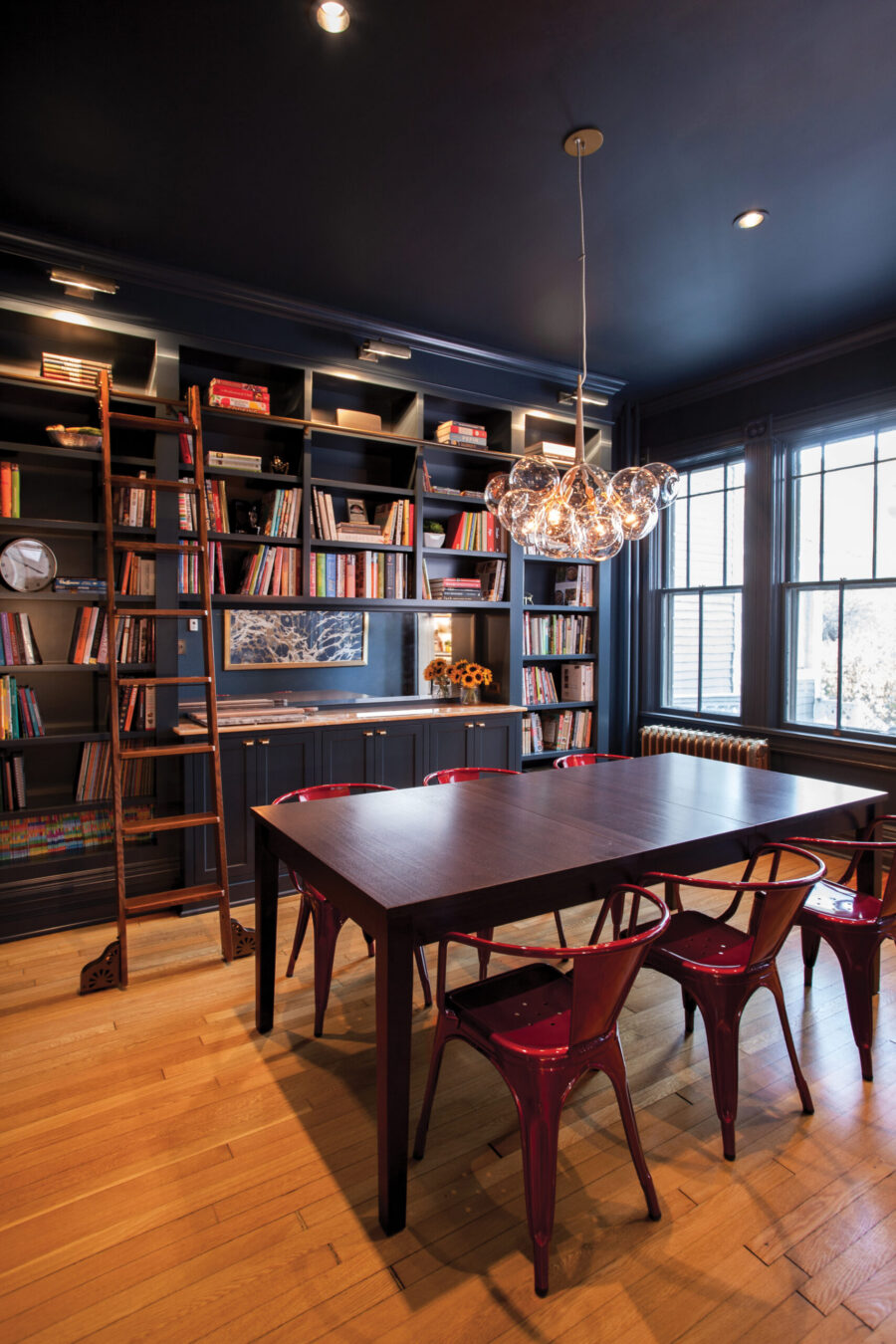 Dark built-in bookshelves, dining table, red chairs, chandelier. Twin Cities remodel.