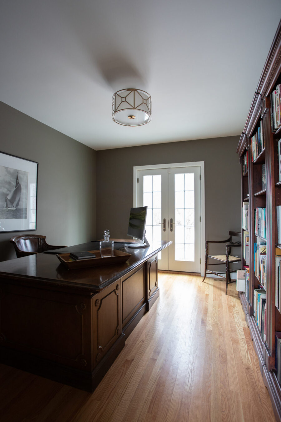Refined office design-build: dark desk, light flooring, French doors.